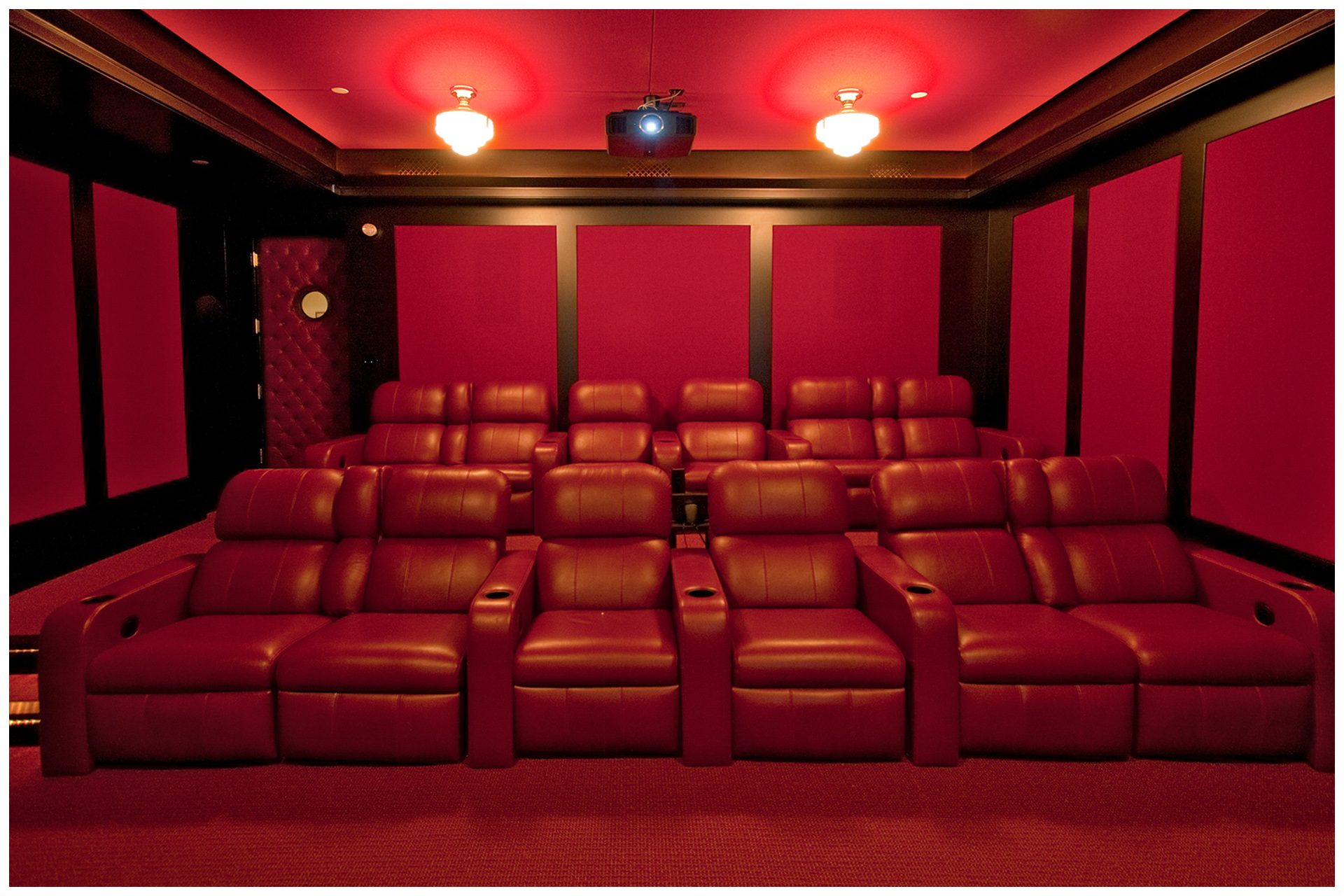 DEDICATED BASEMENT THEATER 12 seat dedicated basement theater with Acoustic paneling to limit sound intrusion outside the room. Front Speaker elements are enclosed into cabinetry and all other  speakers are placed under acoustical panels.Screen and seating are placed on the right side of the room to allow a wide isle leading to exit door in so doing, seats in the center are centered on the screen and front speakers.System is enclosed in an adjacent closet. JBL Synthesis speakers elements are hidden behind fabric in custom wall panelings.