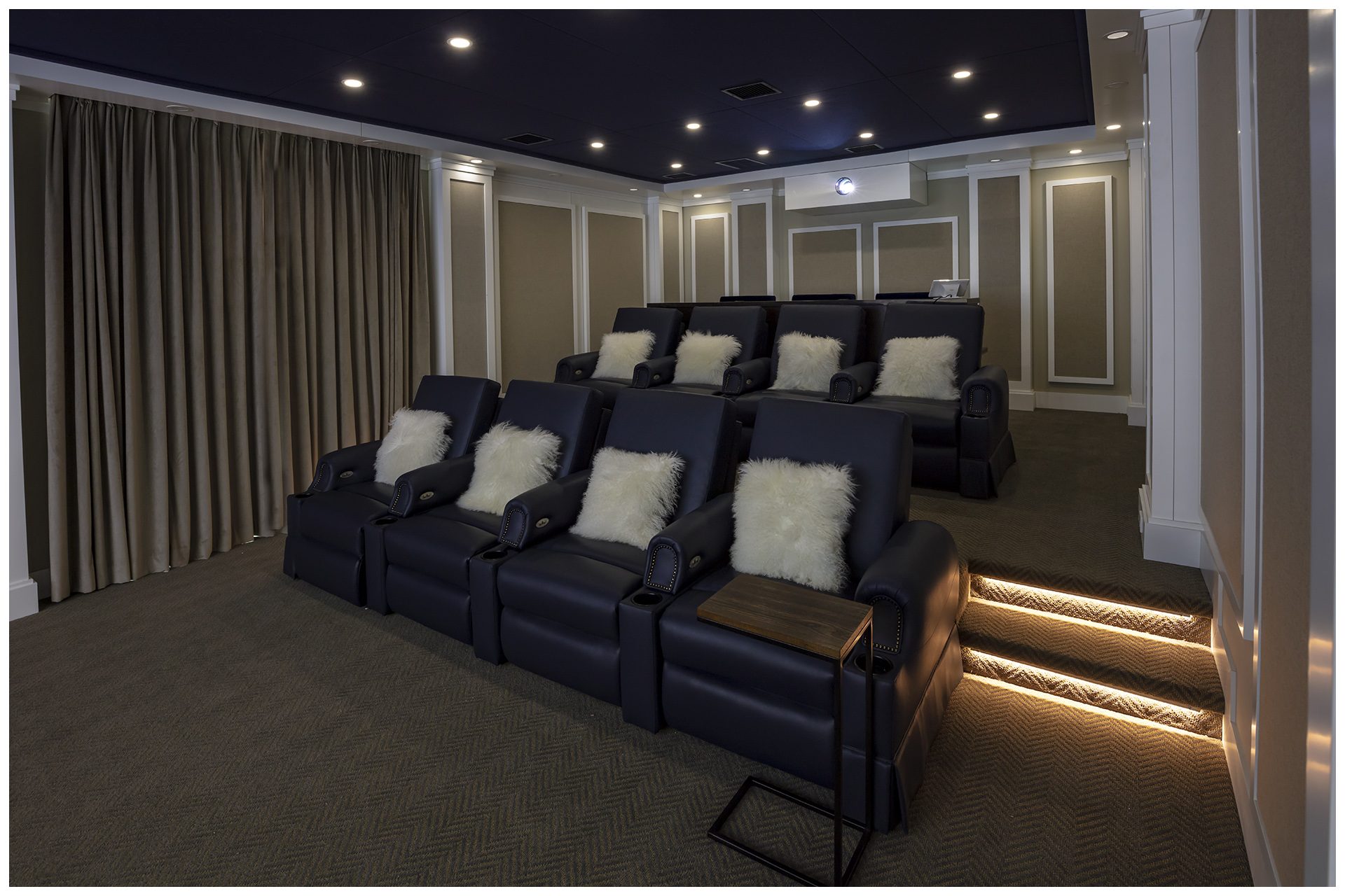 THEATER IN A DEDICATED ROOMProjector is enclosed in a sealed enclosure in the back to prevent projector noise to be audible in the room.  Electronic side drapes allow day light to come in as this room is on the main floor of the residence and owners wished for it to remain bright, open and inviting when theater is not in use.