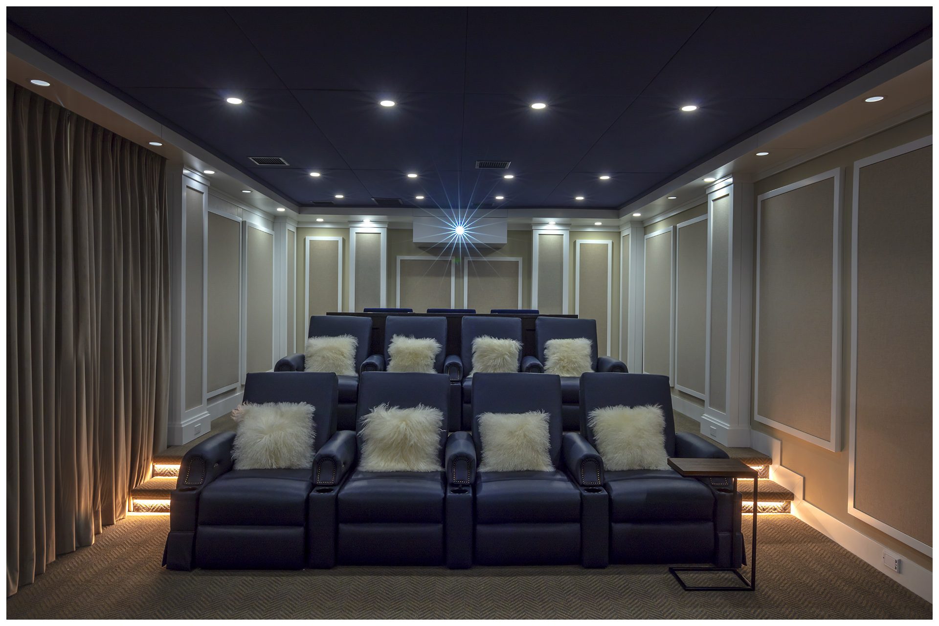 THEATER IN A DEDICATED ROOMHidden panels in the rear open to system elements where the owners are able to insert a DVD locally.  Four sets of lights offer several modes of lighting for the room. JBL Synthesis speakers elements are all enclosed behind fabric in custom paneling from Acoustic Innovations.